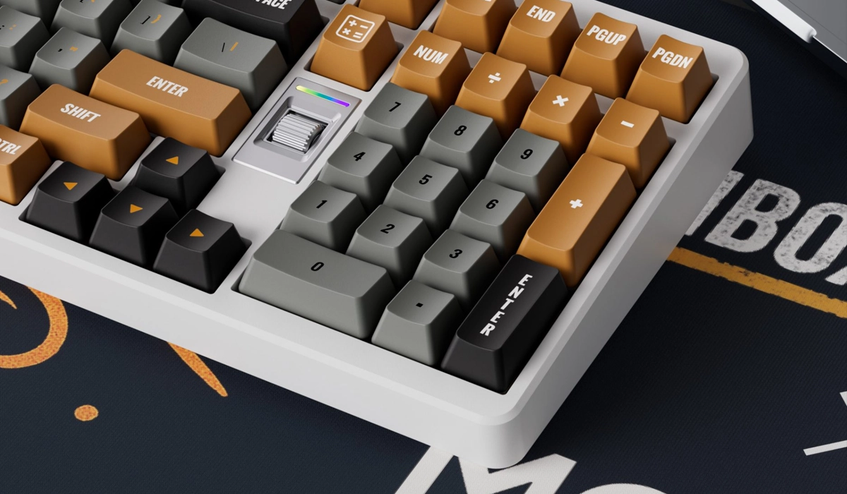 Klawiatura mechaniczna z klawiszami w odcieniach brązu, szarości i czerni oraz srebrnym pokrętłem.